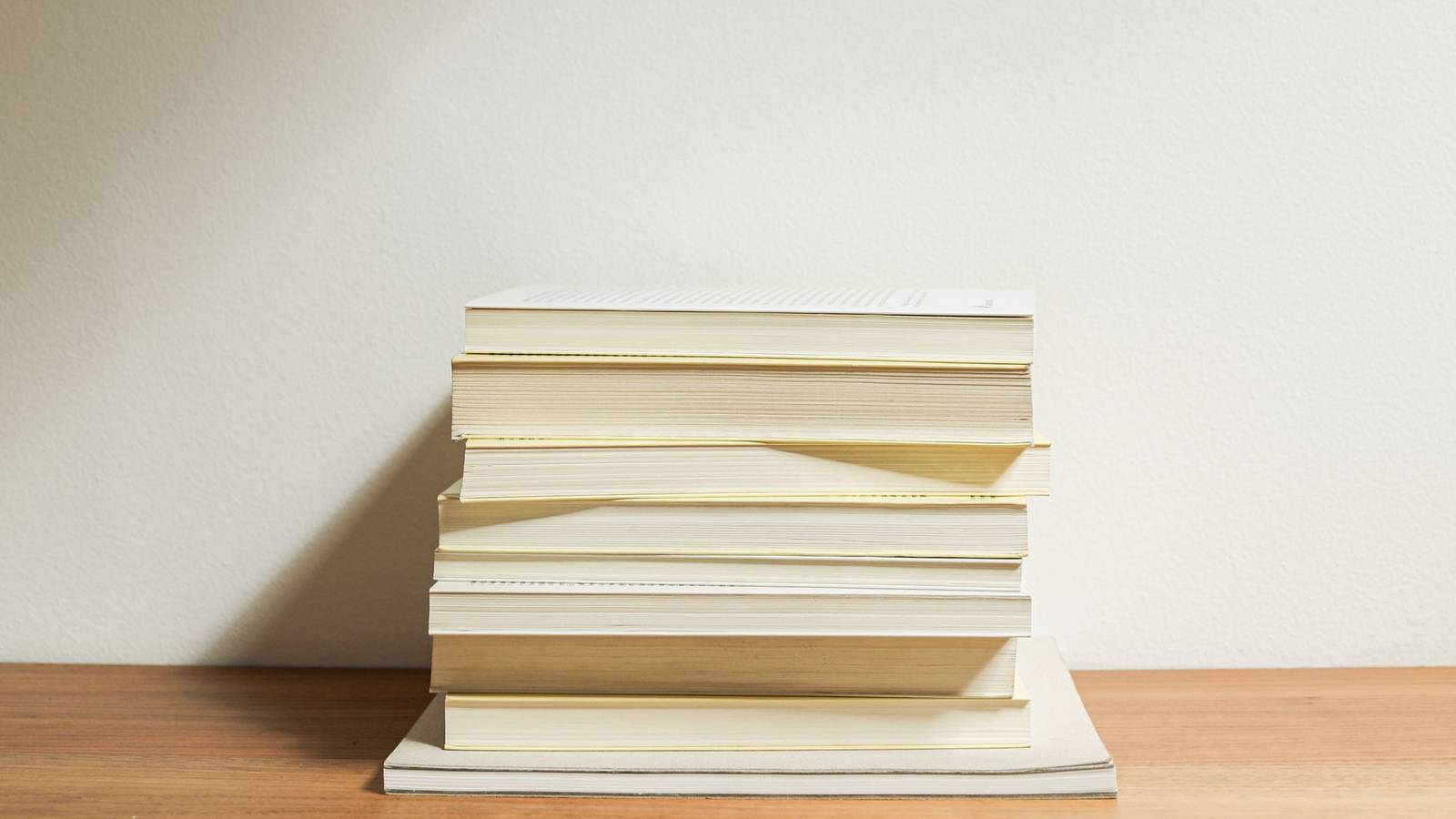 木の棚の上に積み重ねられた問題集や本。過去問を年度ごとに解き進めるイメージ